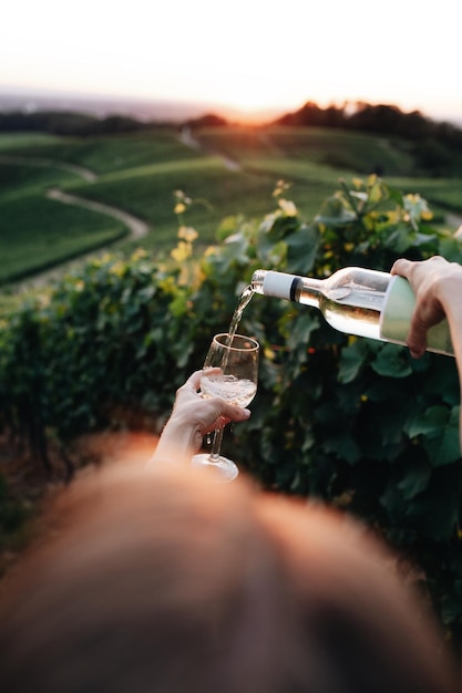 Frau, die Wein in ein Glas gegen die Landschaft gießt