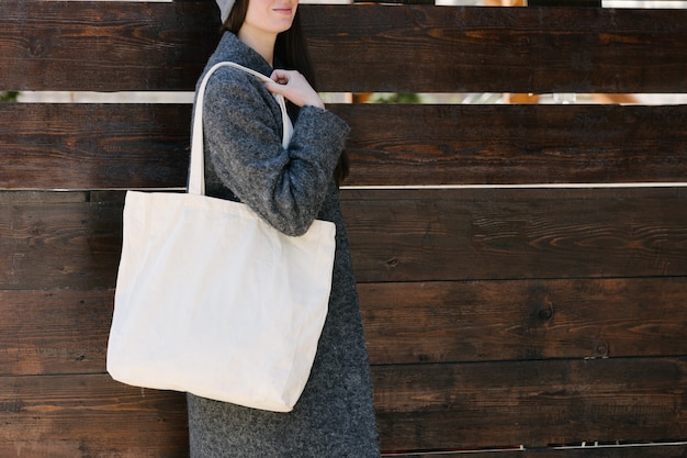 Frau, die weiße Textil-Einkaufstasche Öko-Tasche im Stadtgebiet hält