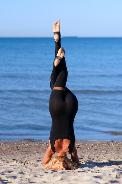 Frau, die Yoga asana am Strand tut