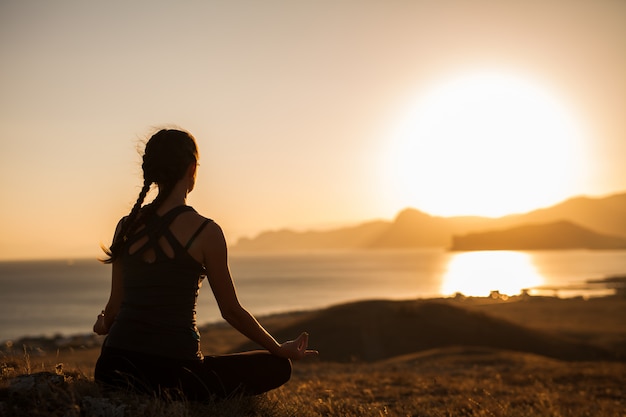 Frau, die Yoga auf der Natur im Freien bei Sonnenaufgang tut