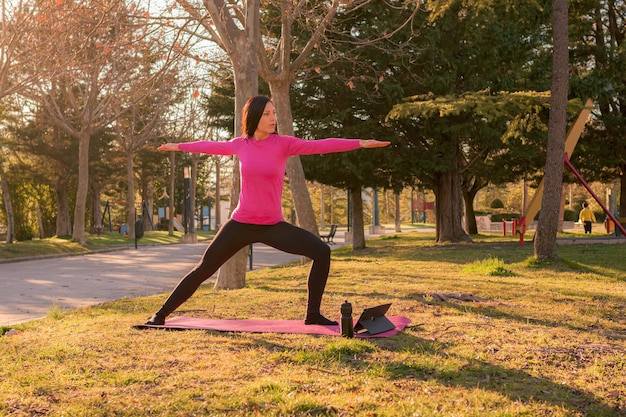 Frau, die Yoga-Übungen in einem Park bei Sonnenuntergang durchführt