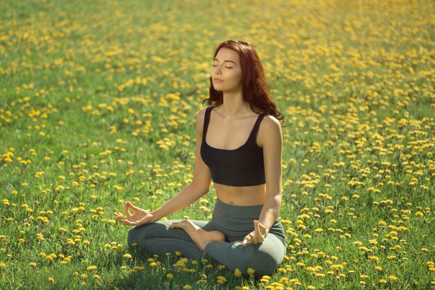 Frau, die Yoga draußen in einem Park praktiziert