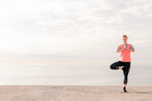 Frau, die Yoga-Gleichgewicht bei Sonnenaufgang praktiziert