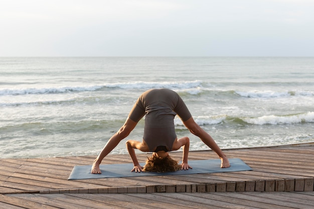 Frau, die Yoga in Richtung Meer tut