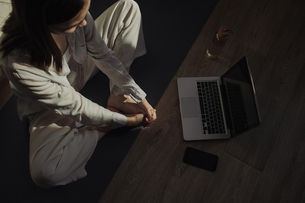 Frau, die Yoga macht und Unterricht auf dem Laptop anschaut, während sie die Beine streckt