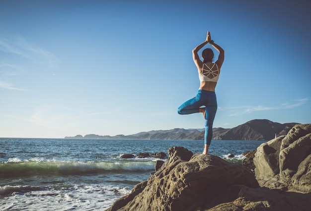 Frau, die Yoga-Posen auf einem Leuchtfeuer macht