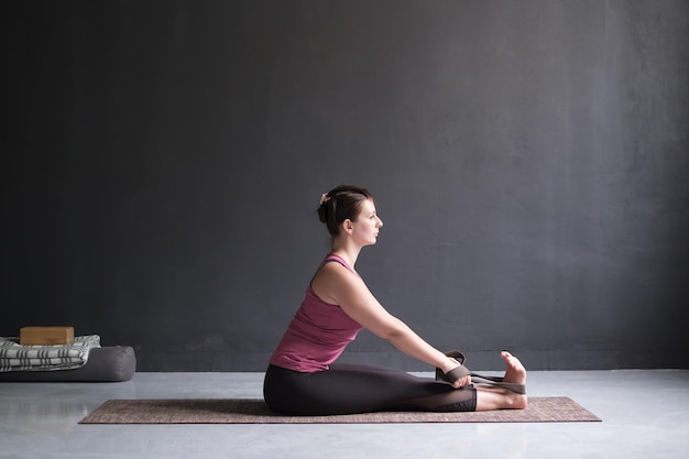 Frau, die Yoga praktiziert Sitzende Vorwärtsbeuge-Pose