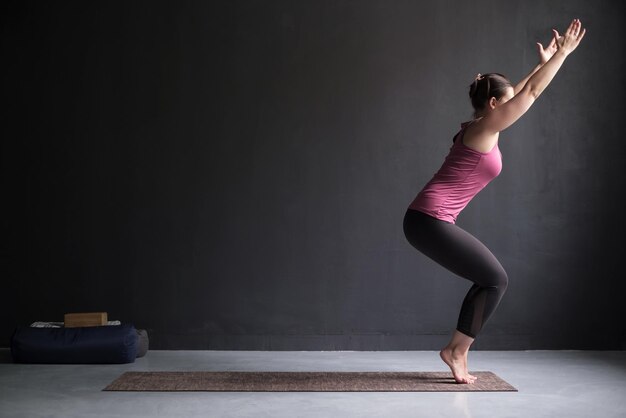 Frau, die Yoga praktiziert und Stuhlübungen in Utkatasana-Pose macht