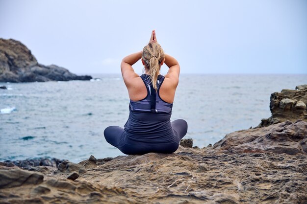 Frau, die Yoga vor dem Meer praktiziert