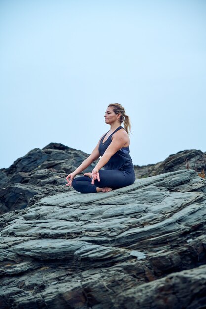 Frau, die Yoga vor dem Meer praktiziert