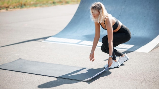 Frau, die Yogamatte auf den Boden legt, während sie sich auf das Training im Sommer vorbereitet