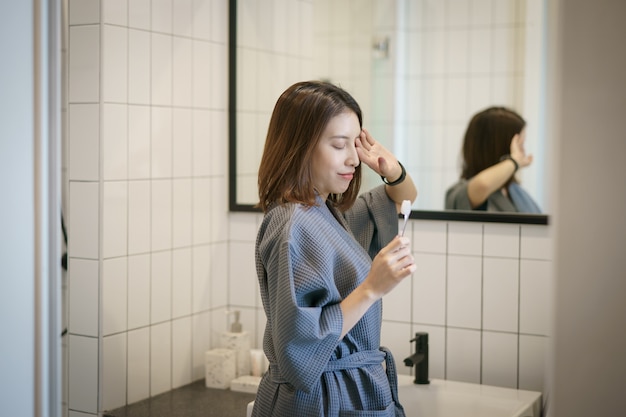 Frau, die Zähne vor ihrem Badezimmerspiegel putzt.
