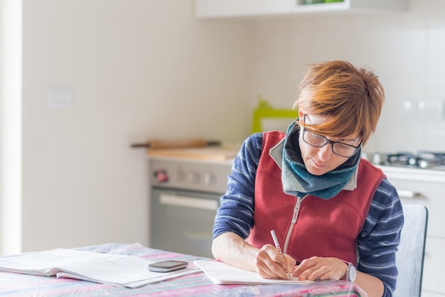 Frau, die zu Hause arbeitet, Dokumente liest und handschreibt