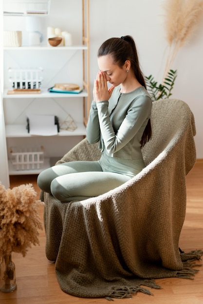 Frau, die zu Hause auf Stuhl meditiert