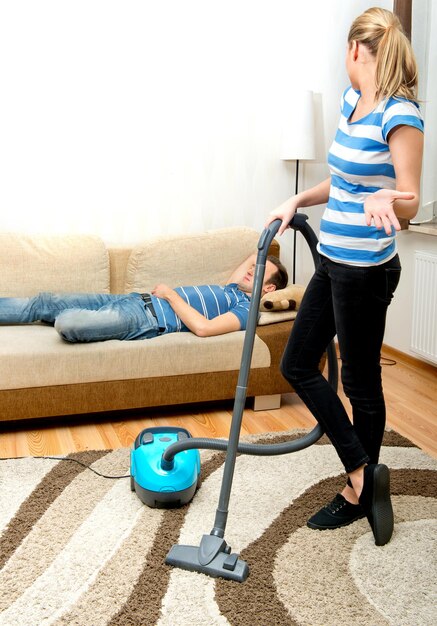 Foto frau, die zu hause einen staubsauger auf einem teppich benutzt