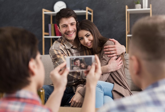 Frau, die zu Hause Foto von Liebespaar auf dem Handy macht