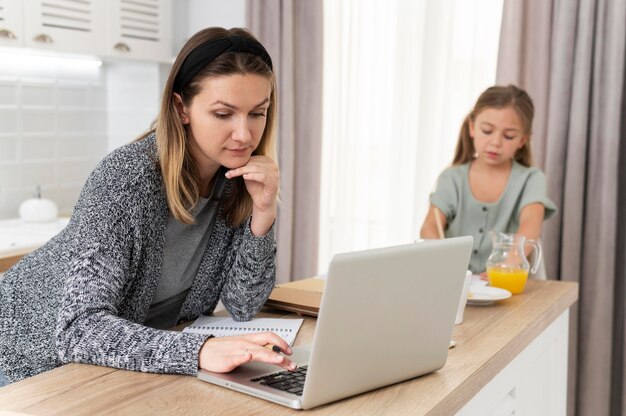 Frau, die zu Hause mit mittlerem Schuss des Kindes arbeitet