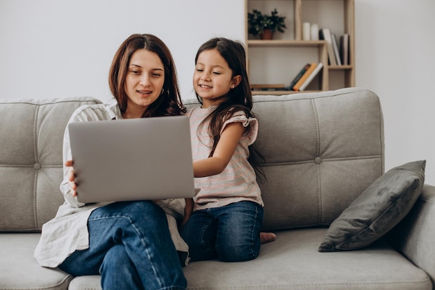 Frau, die zu Hause mit Tochter online am Laptop arbeitet