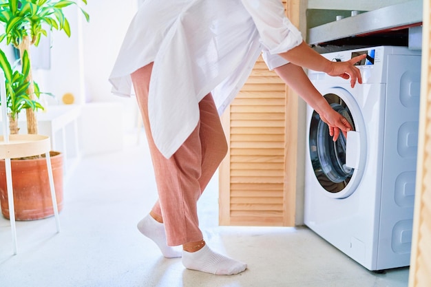 Foto frau, die zu hause moderne waschmaschine für wäsche verwendet