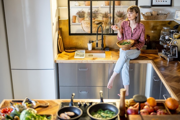 Foto frau, die zu hause salat in der modernen küche isst