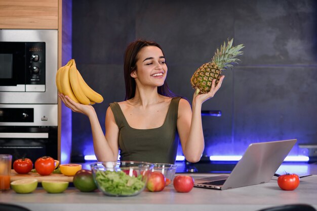 Frau, die zwischen nachtisch und früchten am tisch in der küche wählt. gesunde ernährung