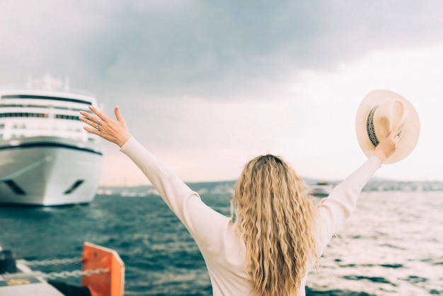 Foto frau, eine touristin, die vor einem großen kreuzfahrtschiff steht