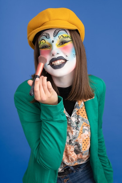 Frau entschädigt für Karneval auf blauem Hintergrund hält Make-up-Pinsel und lächelt