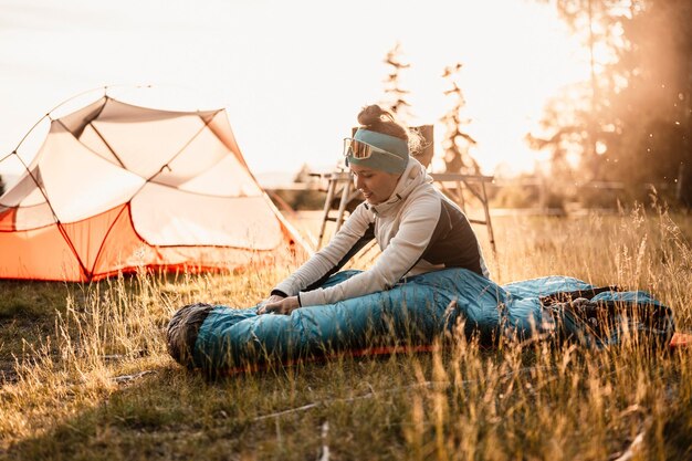 Frau entspannt und liegt in einem Schlafsack im Zelt Sunset Camping im Wald Berge Landschaft Reisen Lifestyle Camping Sommerreisen Outdoor-Abenteuer