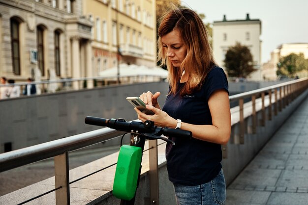 Frau entsperrt Elektroroller zum Mieten mit einer Smartphone-App