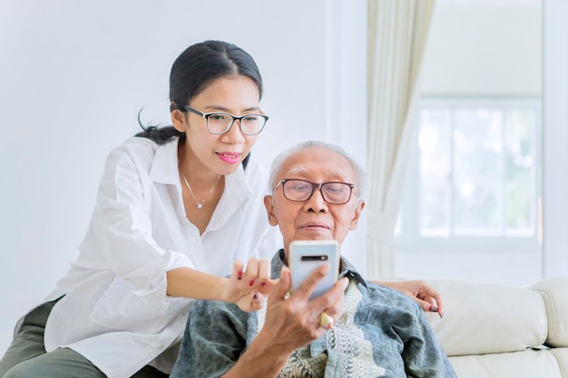 Frau erklärt ihrem Vater, wie man das Handy benutzt