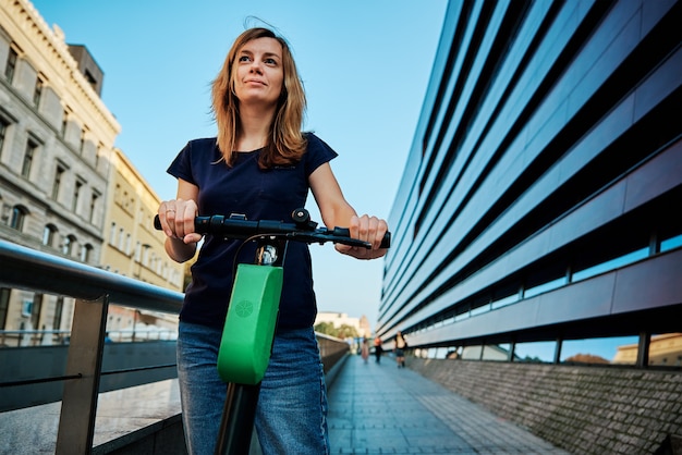 Frau fährt auf einem gemieteten Elektroroller in der Stadt