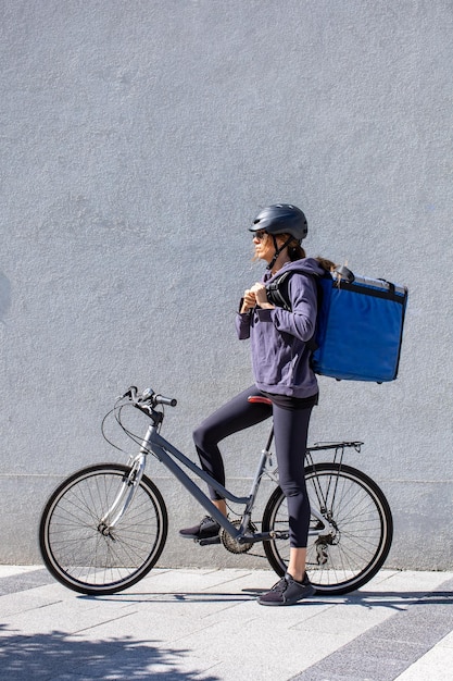 Foto frau fährt fahrrad und liefert bestellungen in der stadt