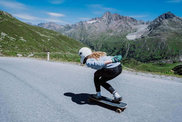 Foto frau fährt skateboard und macht tricks zwischen den kurven auf einem bergpass