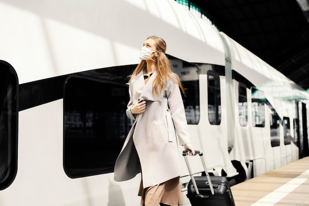 Frau fährt während einer Pandemie mit Gesichtsmaske mit dem Zug