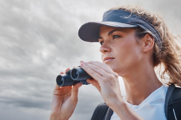 Frau Fernglas und Wandern in der Natur reisen oder im Freien Urlaub oder Reise in Kanada Freiheit bewölkter Himmel und Frau auf Abenteuer Sightseeing oder Trekking und mit Ferngläsern suchen