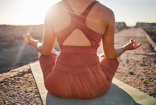 Frau Fitness und Hände in Yoga-Meditation auf der Matte am Strand für spirituelles Wohlbefinden und Wohlbefinden in der Natur Hand der weiblichen Yogi zurück in ruhiger Meditation für gesundes Bewusstsein oder friedlichen Geist auf Felsen