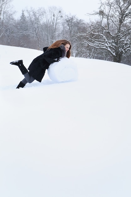 Frau formt einen großen Ball aus dem Schnee