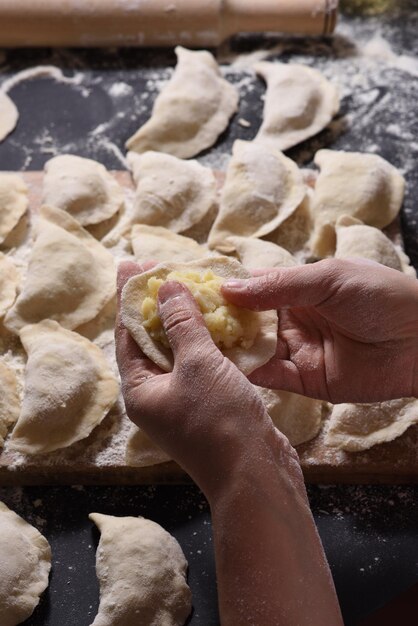 Frau formt Knödel mit handgemachten Kartoffeln auf schwarzem Hintergrund Aufnahme aus dem oberen Winkel Ukrainische Volksküche