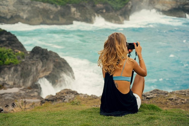 Frau Fotograf Reisende fotografieren Sehenswürdigkeiten vor der Kamera, Angel's Billabong Beach, Insel Nusa Penida, Bali, Indonesien.