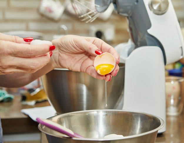 Frau fügt dem Teig ein Ei hinzu, um Käsekuchen mit Schale zuzubereiten, ein Schritt-für-Schritt-Rezept aus dem Internet.