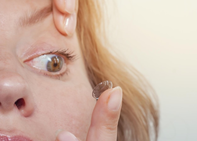 Frau fügt eine Kontaktlinse in das Auge ein Nahaufnahme häusliche Szene Optik Vision Optische Instrumente