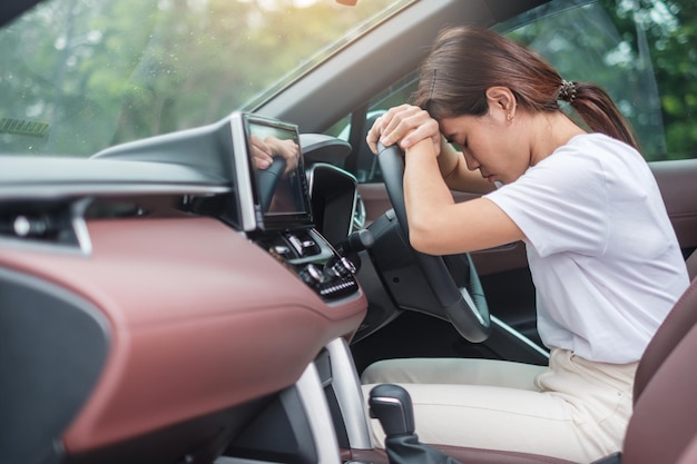 Frau fühlt sich während der Autofahrt gestresst und wütend Asiatisches Mädchen müde und müde mit Kopfschmerzen nach dem Autofahren im Stau Schläfriges Stretching und betrunkenes Konzept