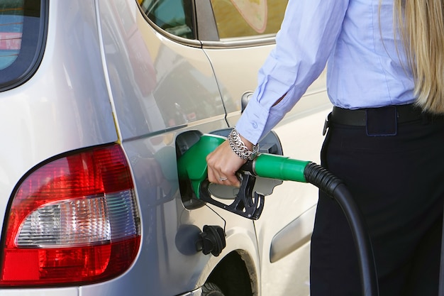 Frau füllt Benzin in ihr Auto an einer Tankstelle Nahaufnahme. Frauenhand, die eine Kraftstoffpumpe an einer Station hält.