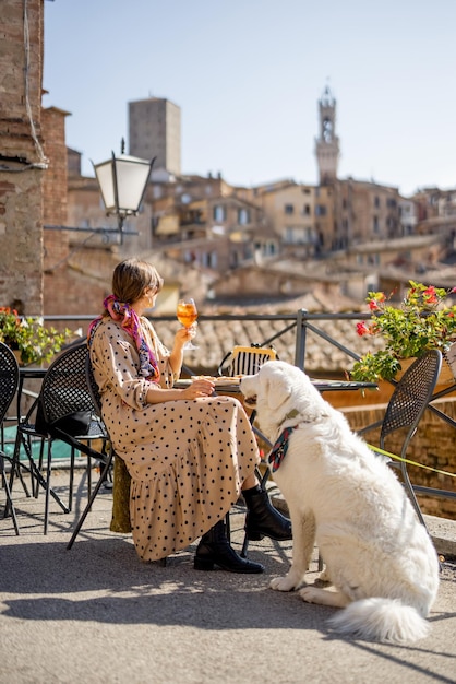 Frau füttert ihren Hund, während sie im Restaurant in Siena, Italien, sitzt