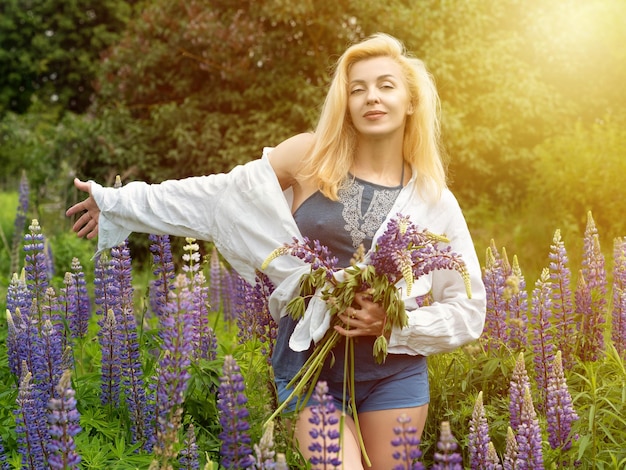 Frau geht im Garten voller Lupinen spazieren