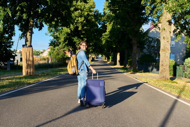 Frau geht mit Koffer und Rucksack auf der Straße auf der Straße Rücksicht Reise Tourismus Reise Urlaub Art Geschäftsreise Konzept