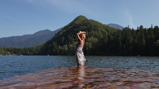 Frau geht mit Sonnenbrille und einem Boho-Seidenschal auf dem Wasser auf dem Pier Mädchen ruht sich auf dem Unterwasserdock aus Flutholz aus Der Bürgersteig ist mit Wasser im See bedeckt