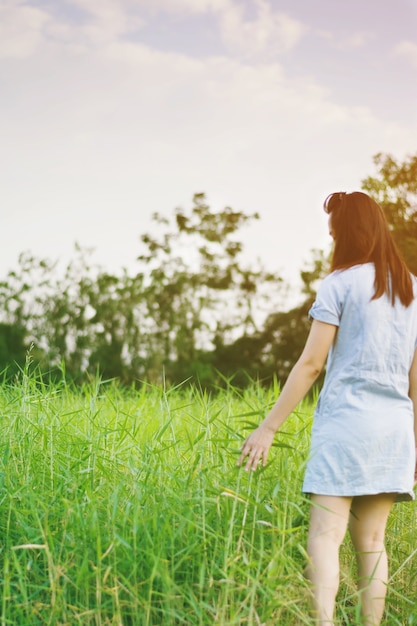 Frau genießen Grasblume in der Wiese bei Sonnenuntergang