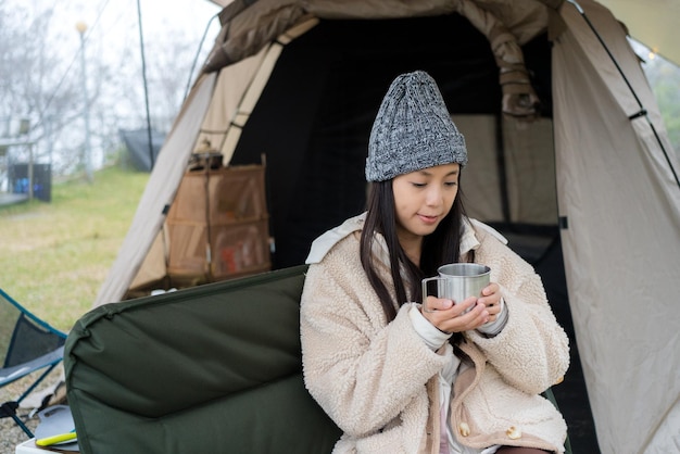 Frau genießt den heißen Kaffee auf dem Campingplatz