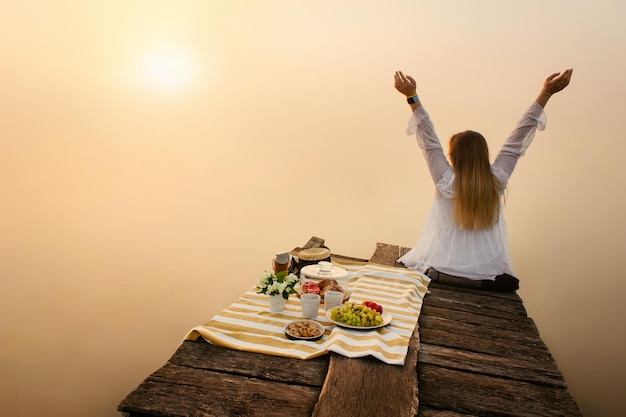 Frau genießt die Natur in der Nähe des nebligen Sees bei Sonnenaufgang